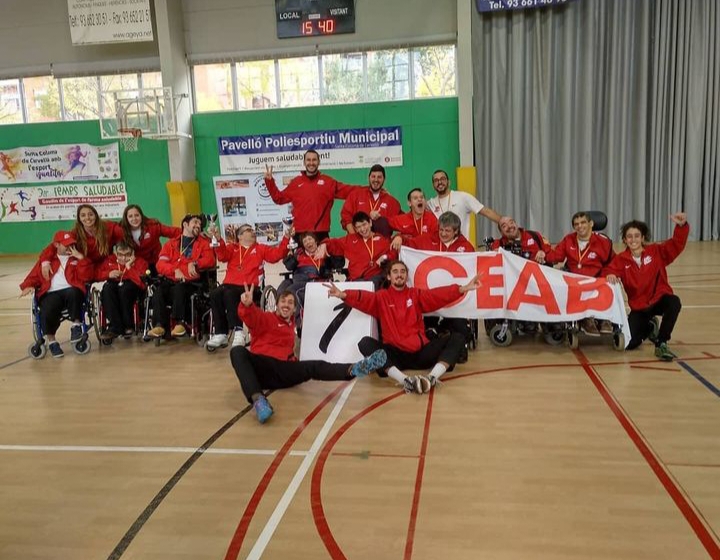 Grupo de personas en silla y técnicos de deporte con una pancarta del club CEAB