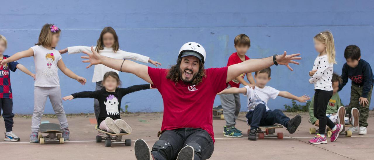 Hombre sentado en un skateboard con los brazos abiertos sonriendo con niños detras